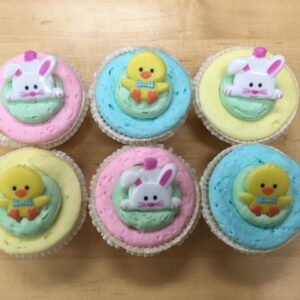 An assortment of pastel cupcakes with bunnies and ducks.