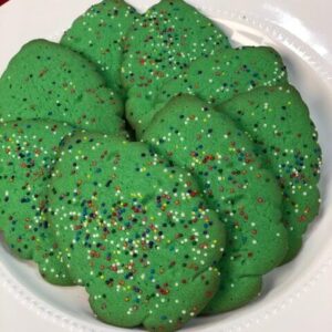 Green tree shaped cookies with rainbow confetti sprinkles.