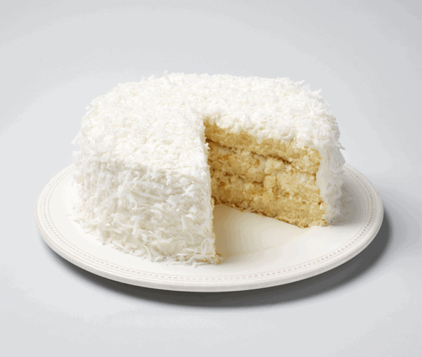 The Ukrop's Coconut Cake with a slice missing to show the layers inside.
