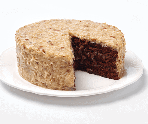 The Ukrop's German Chocolate Cake on a white plate with a slice missing to show the dark chocolate inside.