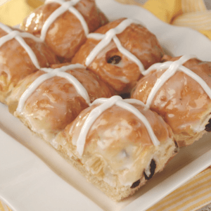 A close up photo of a group of hot cross buns on a plate.