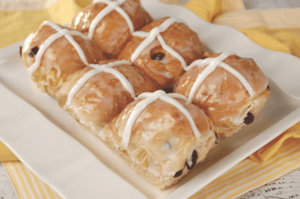 A close up photo of a group of hot cross buns on a plate.