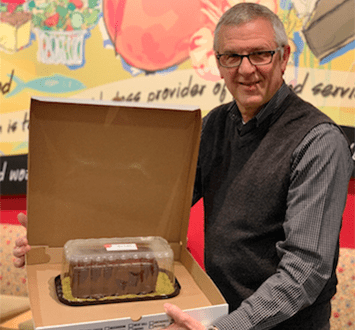 Ukrop's team member Jim Madures holding a Ukrop's Chocolate Bar Cake.