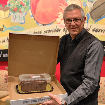 Ukrop's team member Jim Madures holding a Ukrop's Chocolate Bar Cake.