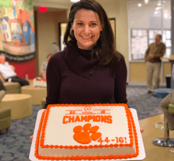 Ukrop's team member Kristin Kirkpatrick holding a Clemson Championship sheet cake.