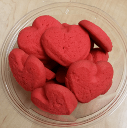 A bowl of small pink heart shaped cookies.