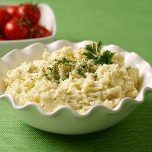 A small dish full of potato salad and garnished with parsley.