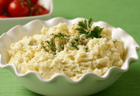 A small dish full of potato salad and garnished with parsley.