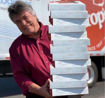 Ukrop's team member Ray Liles holding a tall stack of lemon chess pies.