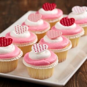 A tray of pink and white cupcakes with hearts on them.